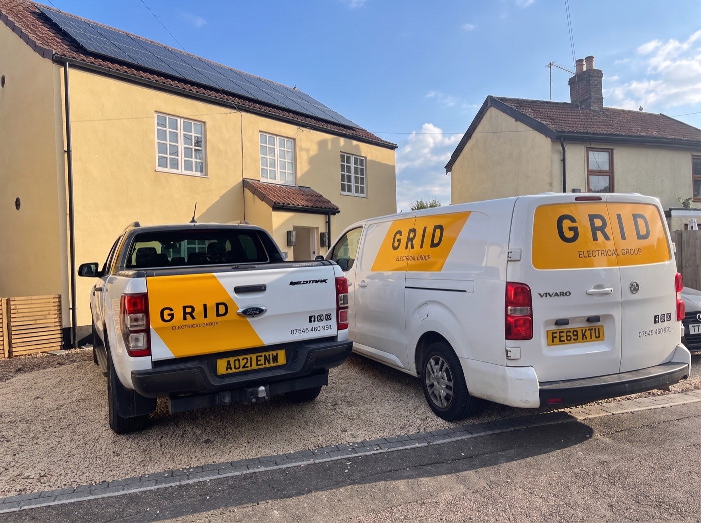 GRID vans outside a Norfolk cottage with solar panels on the roof